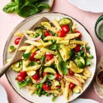Pasta Primavera served in a wide white bowl with colorful summer vegetables, cherry tomatoes, zucchini, asparagus, and fresh basil, drizzled with olive oil and topped with shaved Parmesan