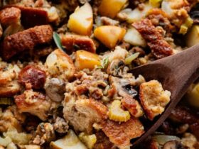Sausage and herb stuffing in a golden baking dish, crispy bread cubes on top, fresh thyme garnish, rustic Thanksgiving table setting