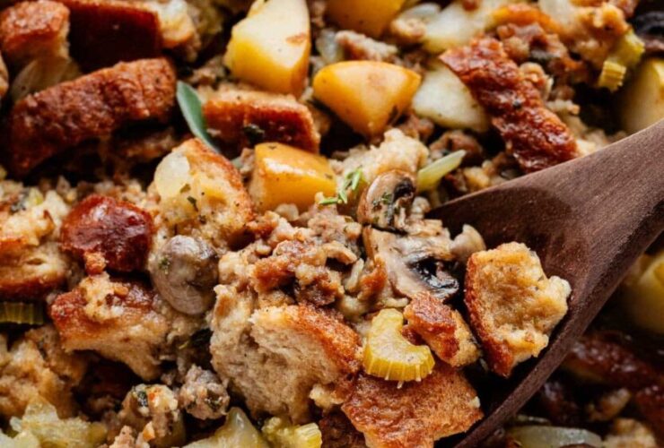 Sausage and herb stuffing in a golden baking dish, crispy bread cubes on top, fresh thyme garnish, rustic Thanksgiving table setting