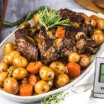 Slow Cooker Beef Stew served in a rustic ceramic bowl with fork-tender beef, golden potatoes, and carrots in a glossy herb-loaded brown gravy, garnished with fresh thyme