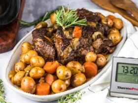 Slow Cooker Beef Stew served in a rustic ceramic bowl with fork-tender beef, golden potatoes, and carrots in a glossy herb-loaded brown gravy, garnished with fresh thyme