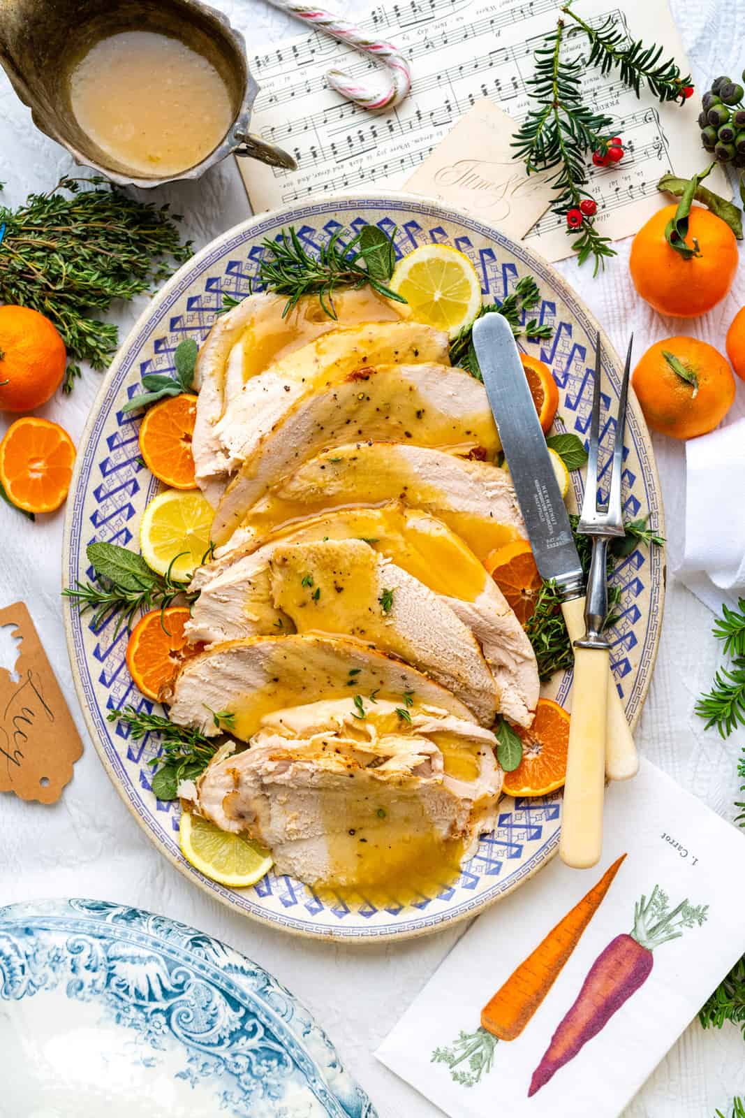 Close-up of sliced slow cooker turkey breast showing juicy interior, golden herb-crusted skin, and rich gravy pooling on a white serving platter with fresh rosemary garnish