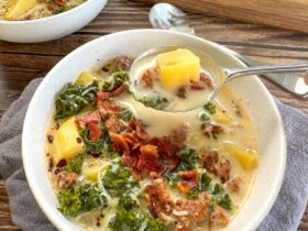 Slow cooker Zuppa Toscana served in a rustic bowl with creamy broth, Italian sausage, potato slices, and wilted kale, garnished with Parmesan and red pepper flakes