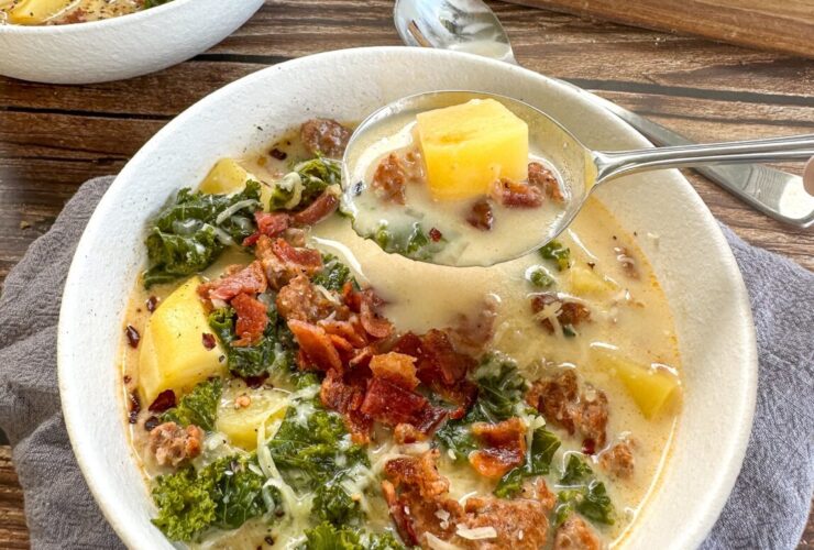 Slow cooker Zuppa Toscana served in a rustic bowl with creamy broth, Italian sausage, potato slices, and wilted kale, garnished with Parmesan and red pepper flakes
