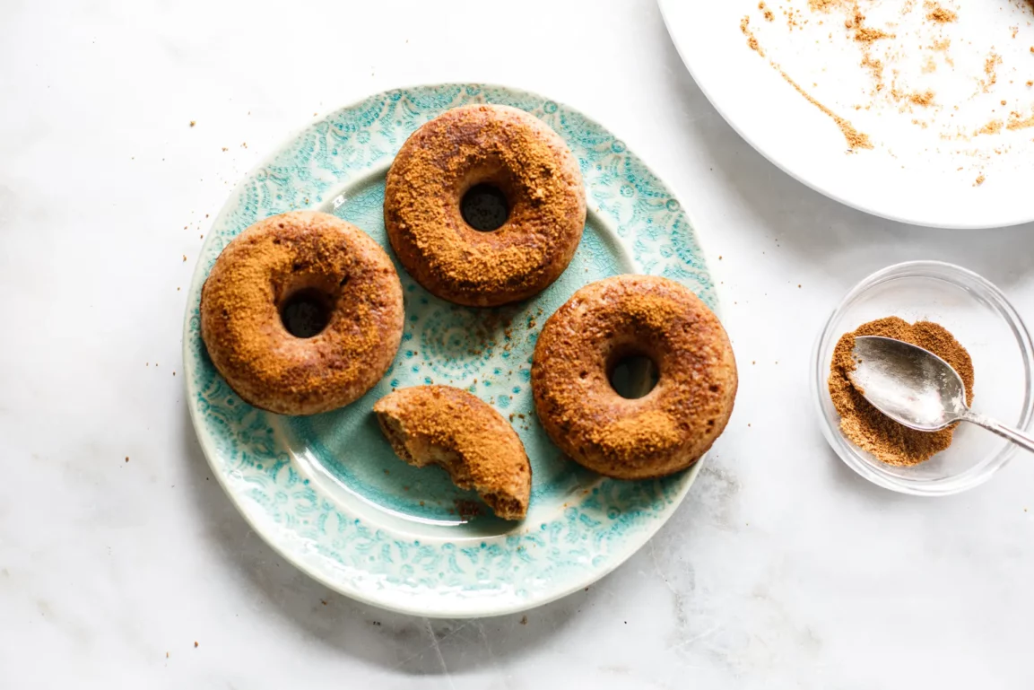 overhead flat lay of apple cider donut ingredients including reduced cider, spices, brown sugar, sour cream, and flour on a marble countertop