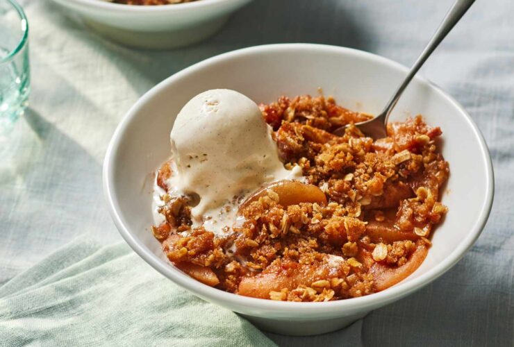 Golden apple crisp fresh from the oven in a white baking dish, topped with a thick buttery oat streusel, served warm with a scoop of vanilla ice cream melting over the top