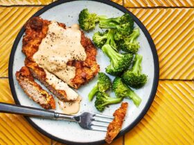 Close-up of chicken fried steak being cut open to reveal a tender interior with white gravy pooling on the plate