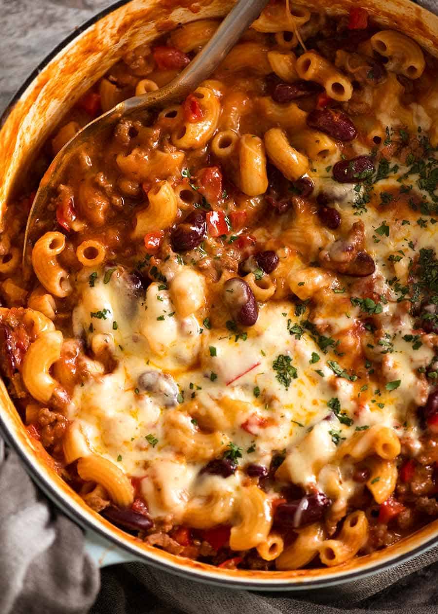 Ingredients for chili mac laid out on a counter — ground beef, spices, canned tomatoes, macaroni, and shredded cheddar