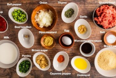 Overhead shot of meatloaf ingredients including ground beef, breadcrumbs, eggs, Worcestershire sauce, onion, and glaze ingredients arranged on a kitchen counter