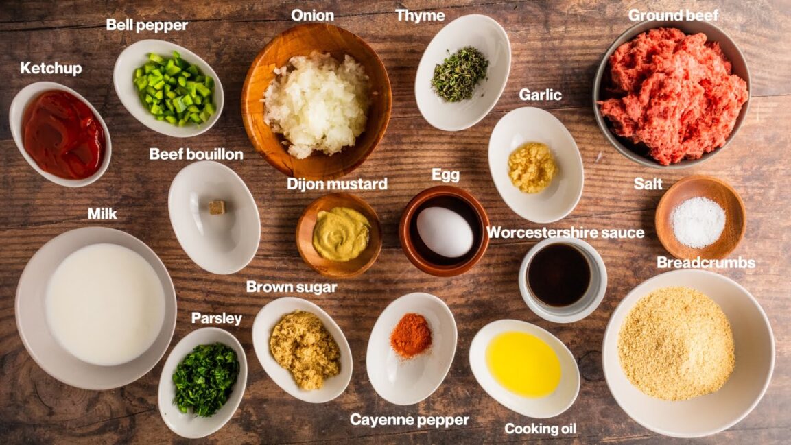 Overhead shot of meatloaf ingredients including ground beef, breadcrumbs, eggs, Worcestershire sauce, onion, and glaze ingredients arranged on a kitchen counter
