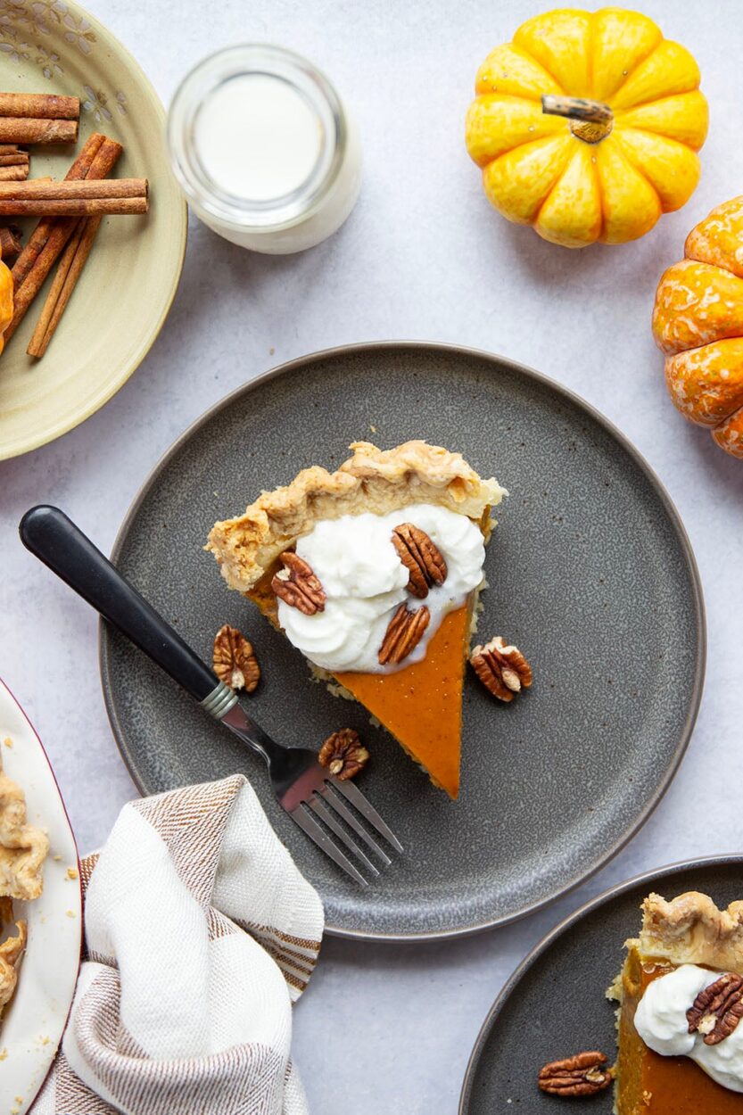 Overhead shot of pumpkin pie filling ingredients — pumpkin purée, eggs, heavy cream, brown sugar, and spices arranged on a marble surface