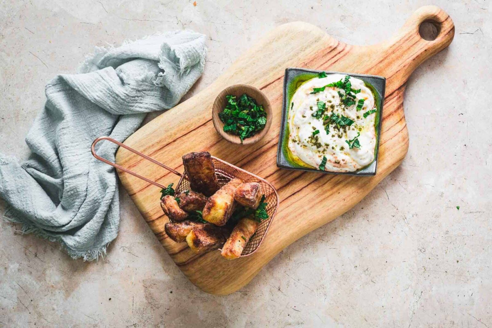 Crispy golden halloumi cheese fries served with a creamy yogurt dipping sauce and fresh herbs on a rustic wooden board