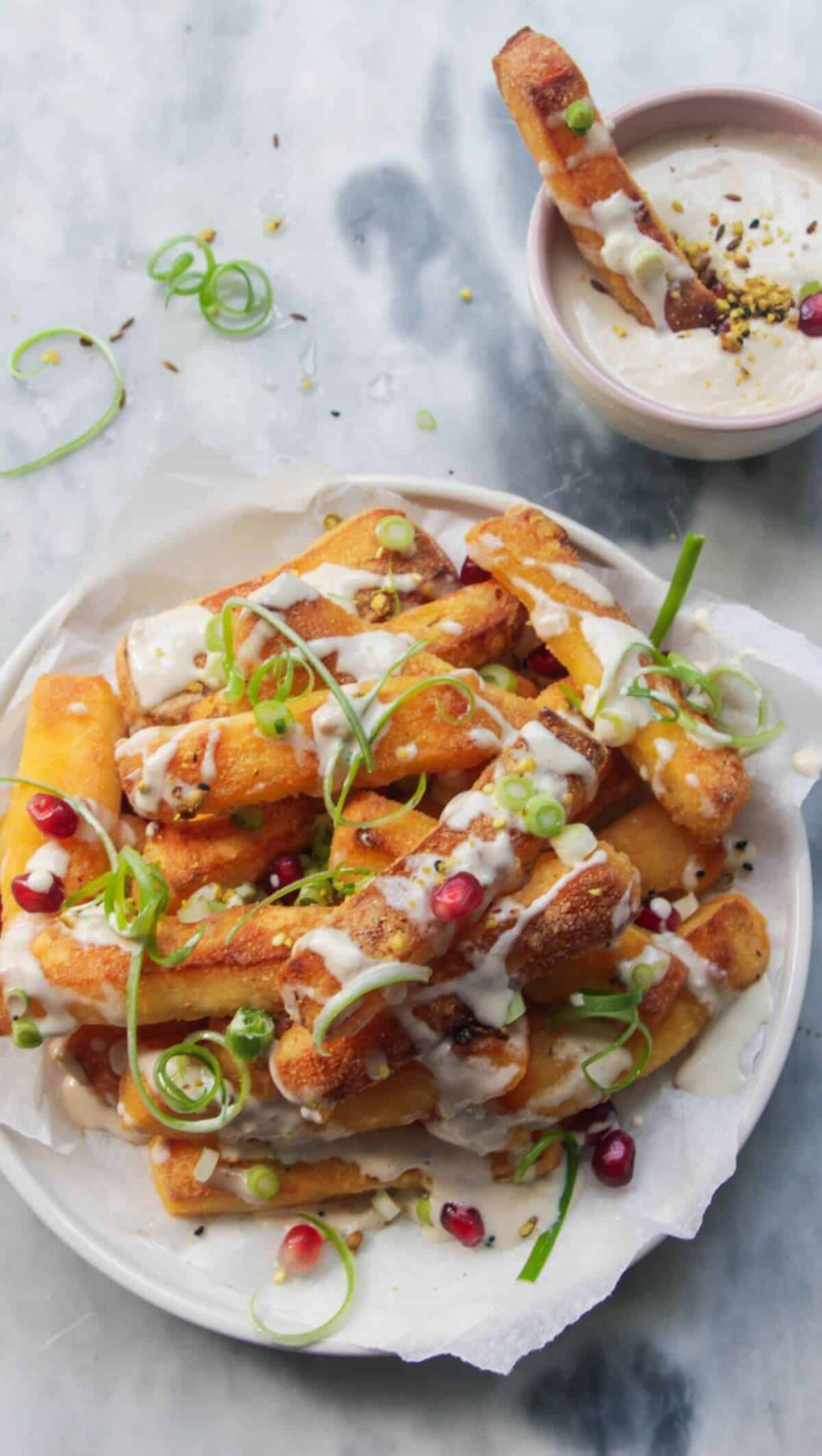 Close-up of crispy halloumi cheese fries with a golden crust, drizzled with honey and scattered with fresh mint leaves and chili flakes
