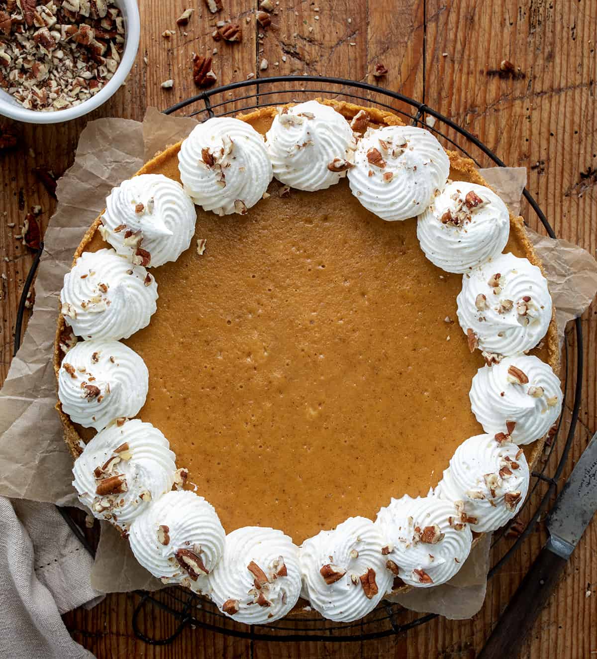 Overhead shot of cheesecake filling ingredients — cream cheese, pumpkin purée, spices, and whipped cream in mixing bowls