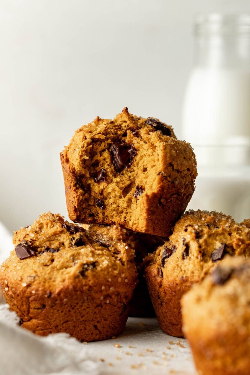 Bakery-style pumpkin chocolate chip muffins with domed tops and melted chocolate chips, cooling on a wire rack