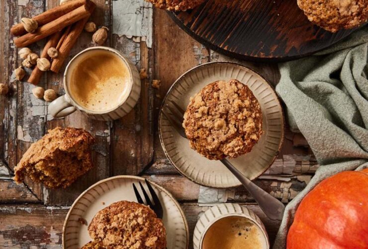 Overhead flat-lay of pumpkin muffin ingredients — pumpkin purée, chocolate chips, brown sugar, eggs, flour, and spices on a wooden surface