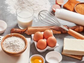 flat lay of five ingredients for butter cookies — butter, sugar, flour, salt, and vanilla extract arranged on a marble surface with a mixing bowl and wooden spoon