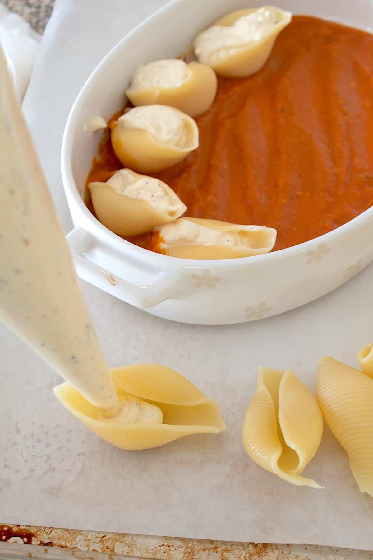 Close-up of a single stuffed shell being lifted from the pan, showing the creamy ricotta filling and stretchy melted mozzarella cheese pull